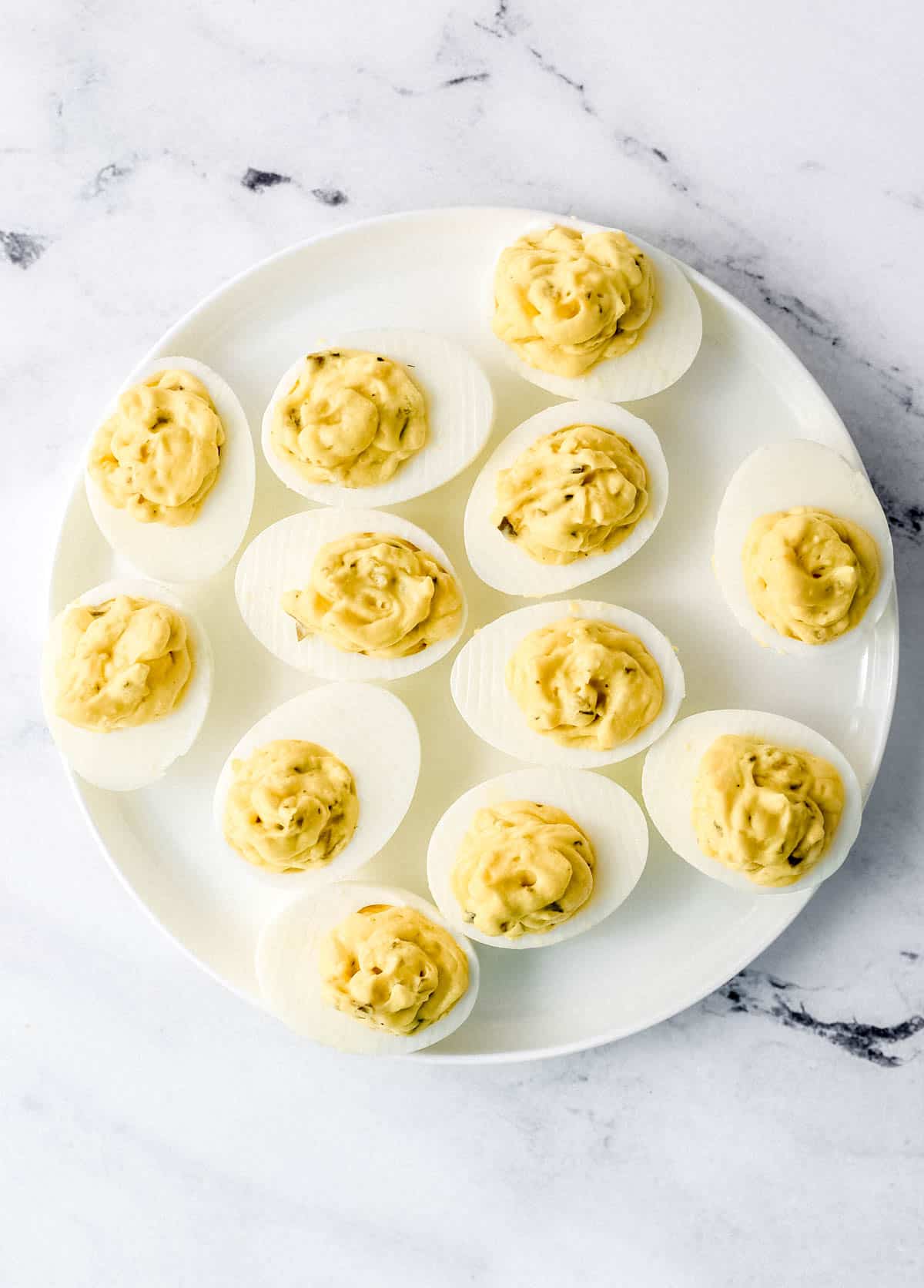 Egg yolk filling piped into the egg white and on a white plate. 