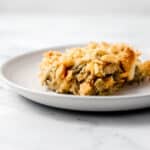 Close up side view of single serving of casserole on white plate.