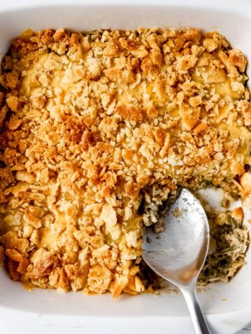 Overhead view of green bean casserole in white baking dish with serving spoon in.