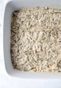 Green bean mixture spread in a white baking dish.