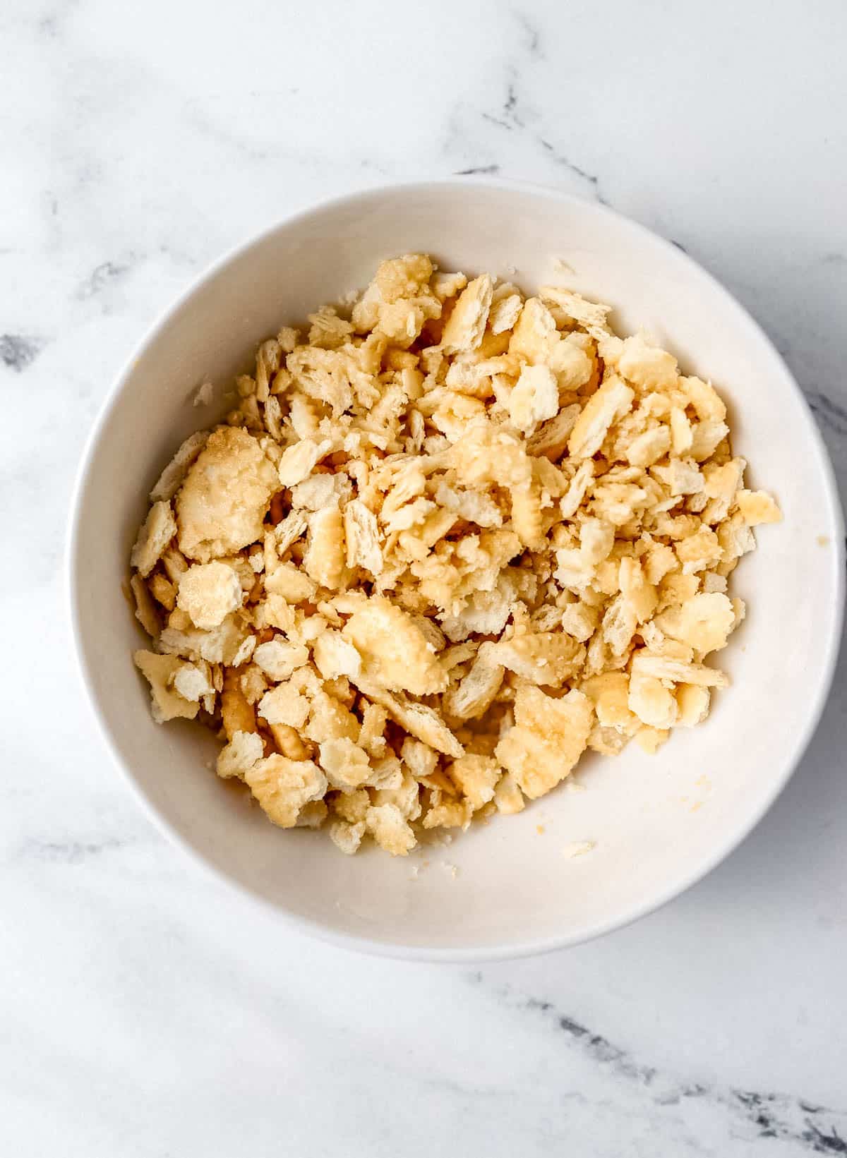 Crushed Ritz crackers and melted butter combined in white bowl. 