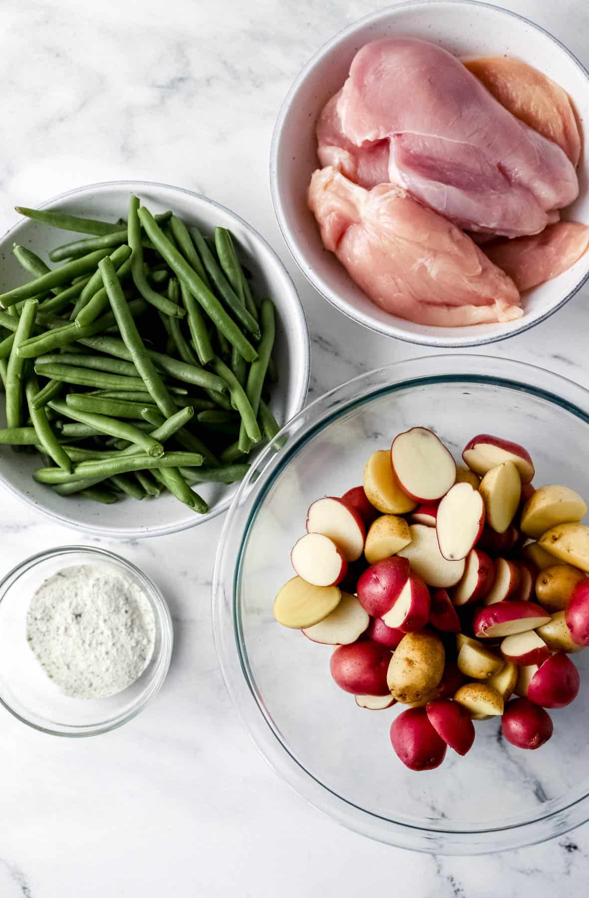 Overhead view to ingredients needed to make recipe in separate bowls on marble surface. 