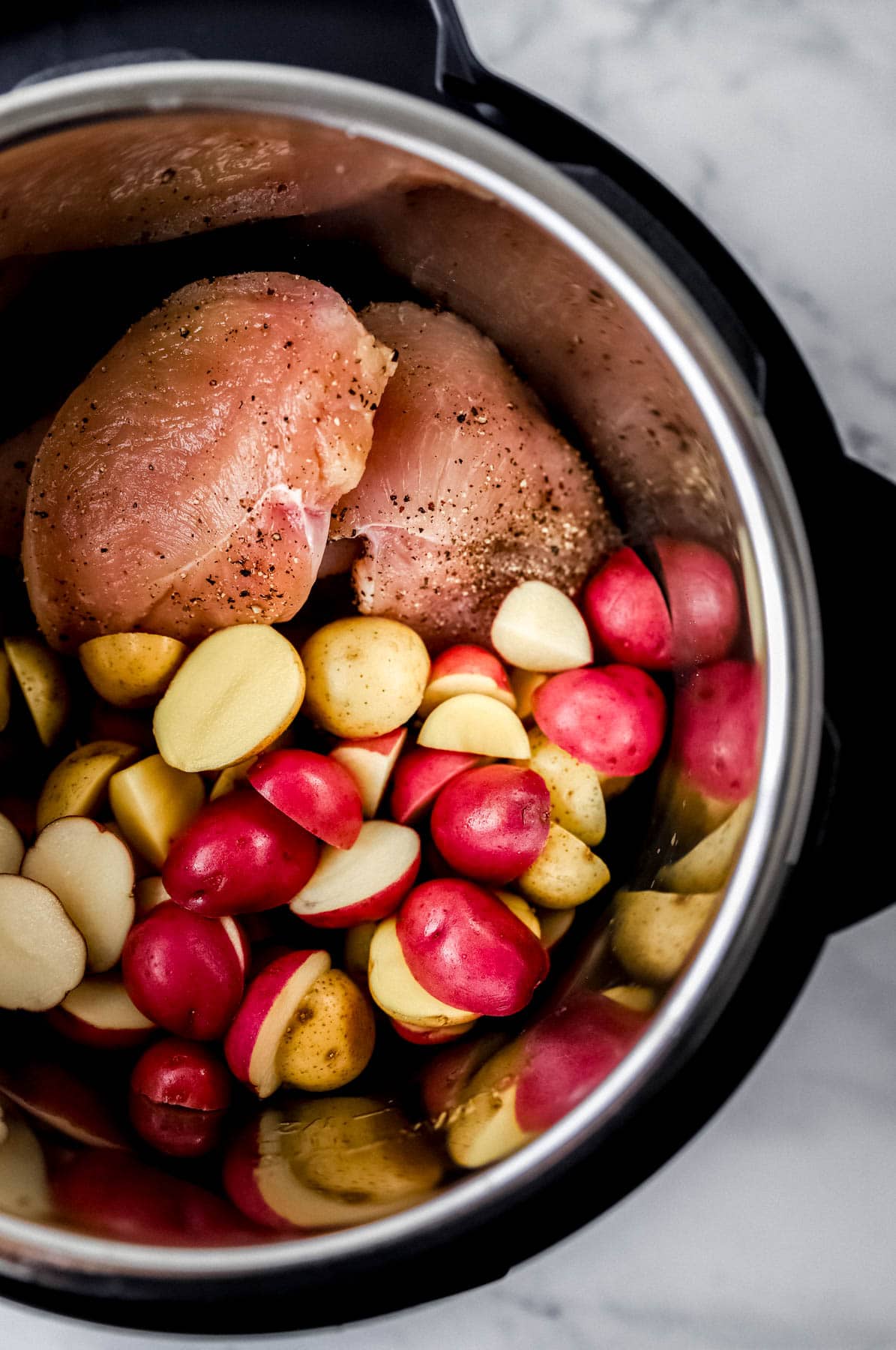 Raw seasoned chicken and potatoes added to instant pot pressure cooker. 