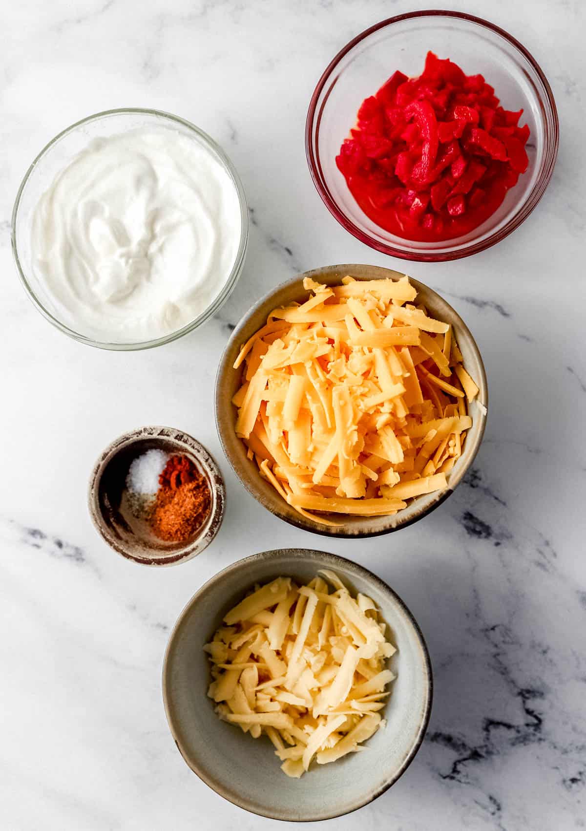 Ingredients needed to make pimento cheese in five separate small bowls. 
