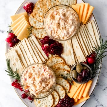 Overhead view of snack board with two small glass bowls of pimento cheese.