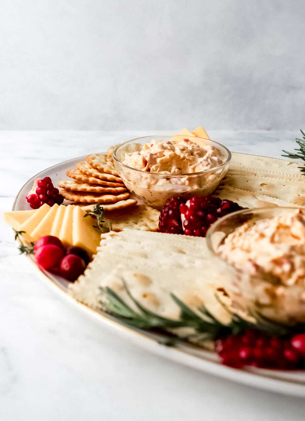 Close up side view of snack board with pimento cheese in glass bowls. 