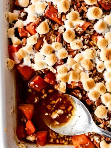 Overhead view of baked sweet potato casserole in baking dish with spoon in it.