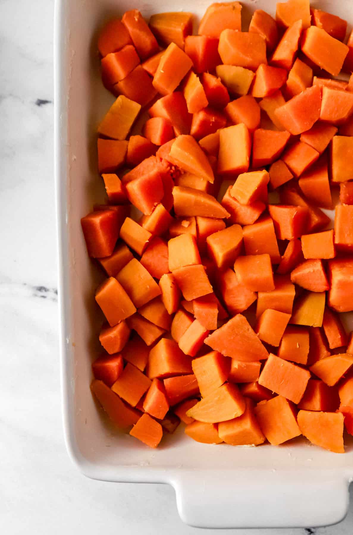 Cooked sweet potato added to the bottom of a buttered baking dish. 