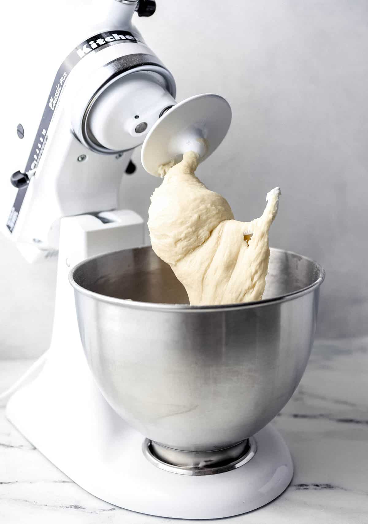 Close up side view of dough in stand mixer with hook attachment. 