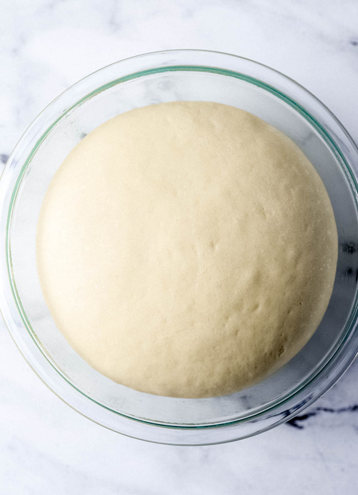 Dough ball in glass bowl after it has had time to rise and double in size. 