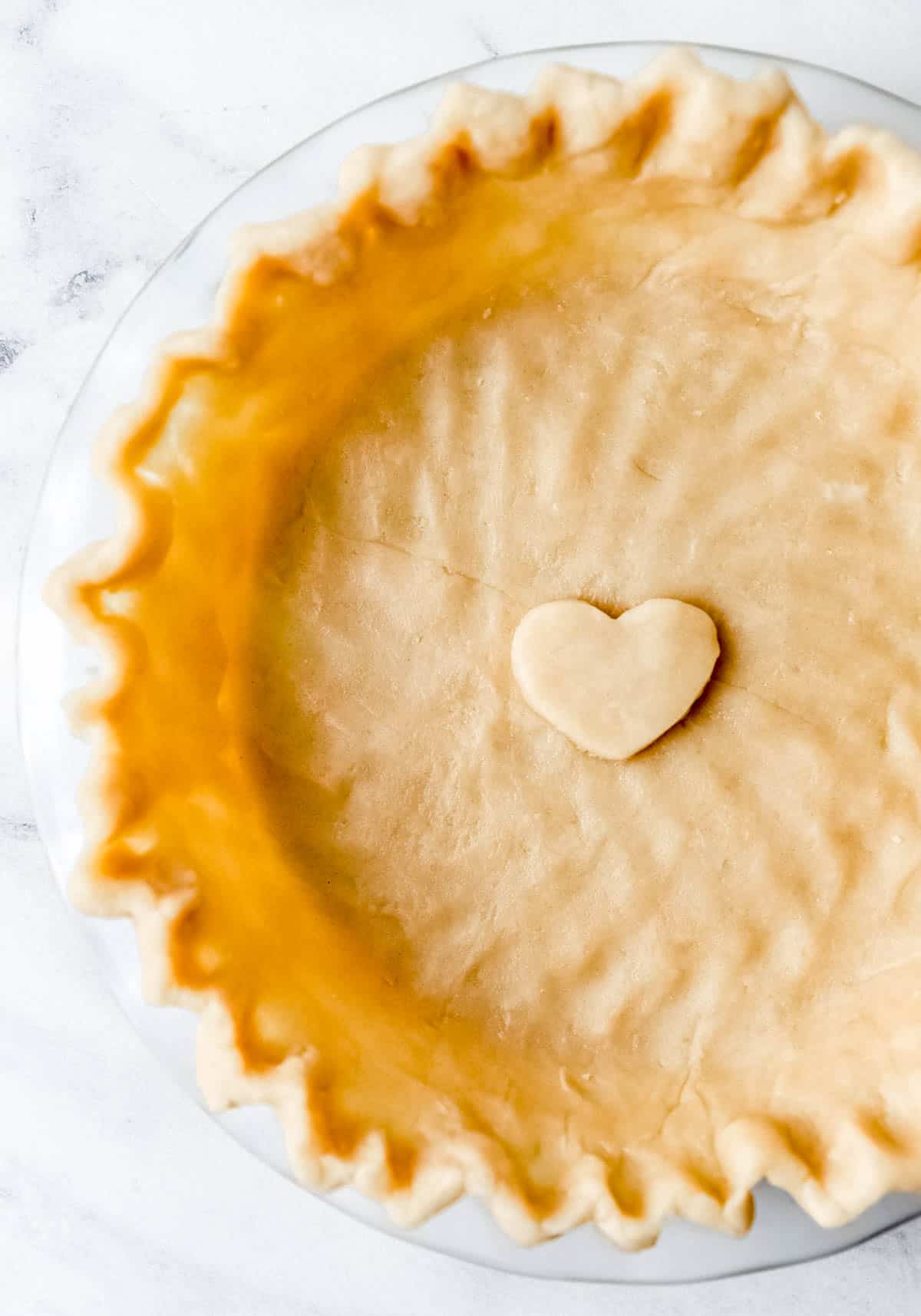 Overhead view of unbaked pie crust in a glass pie plate.