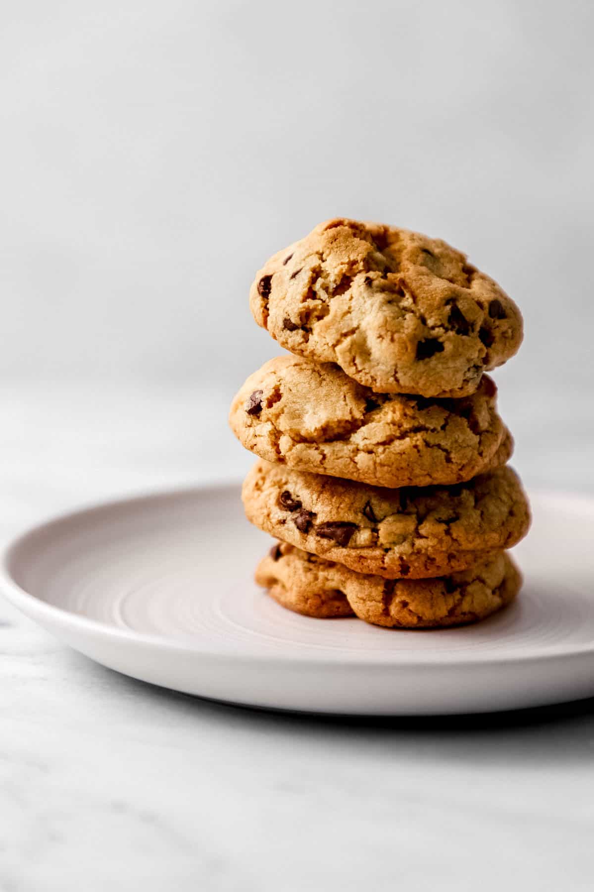 Close up side view of cookies stacked on top of each other on white plate. 