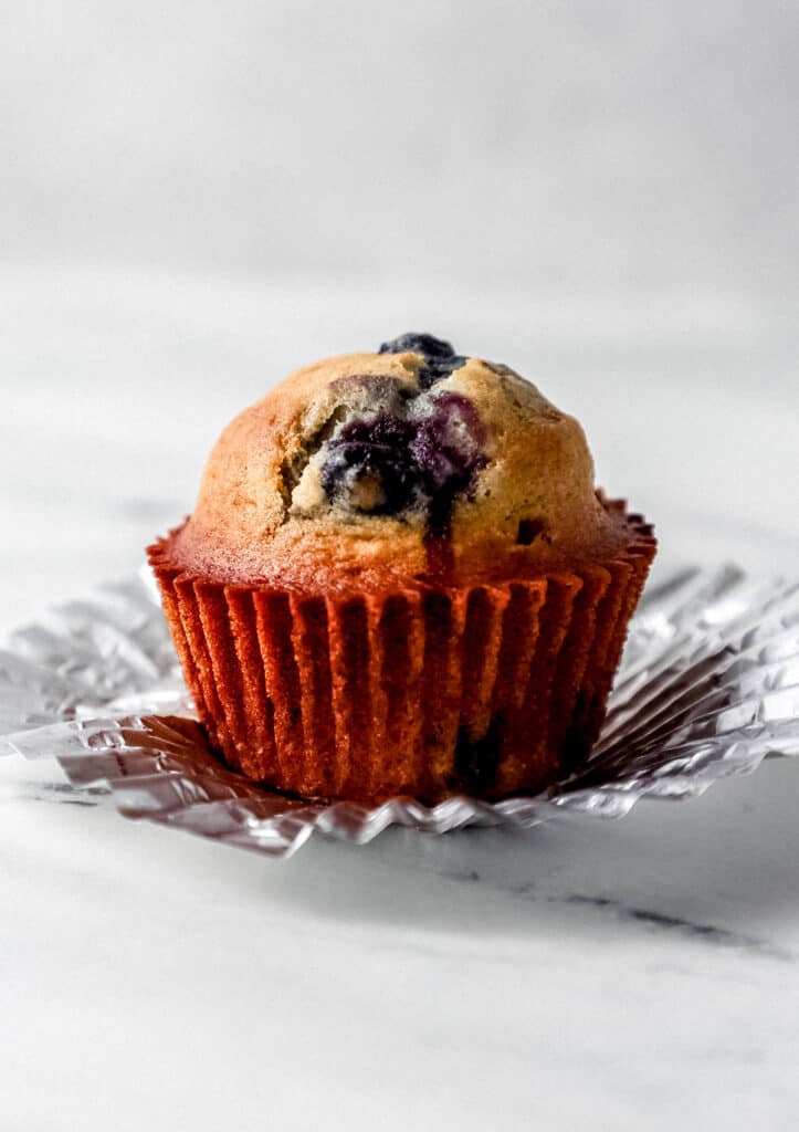 Close up side view of single muffin on top of liner.