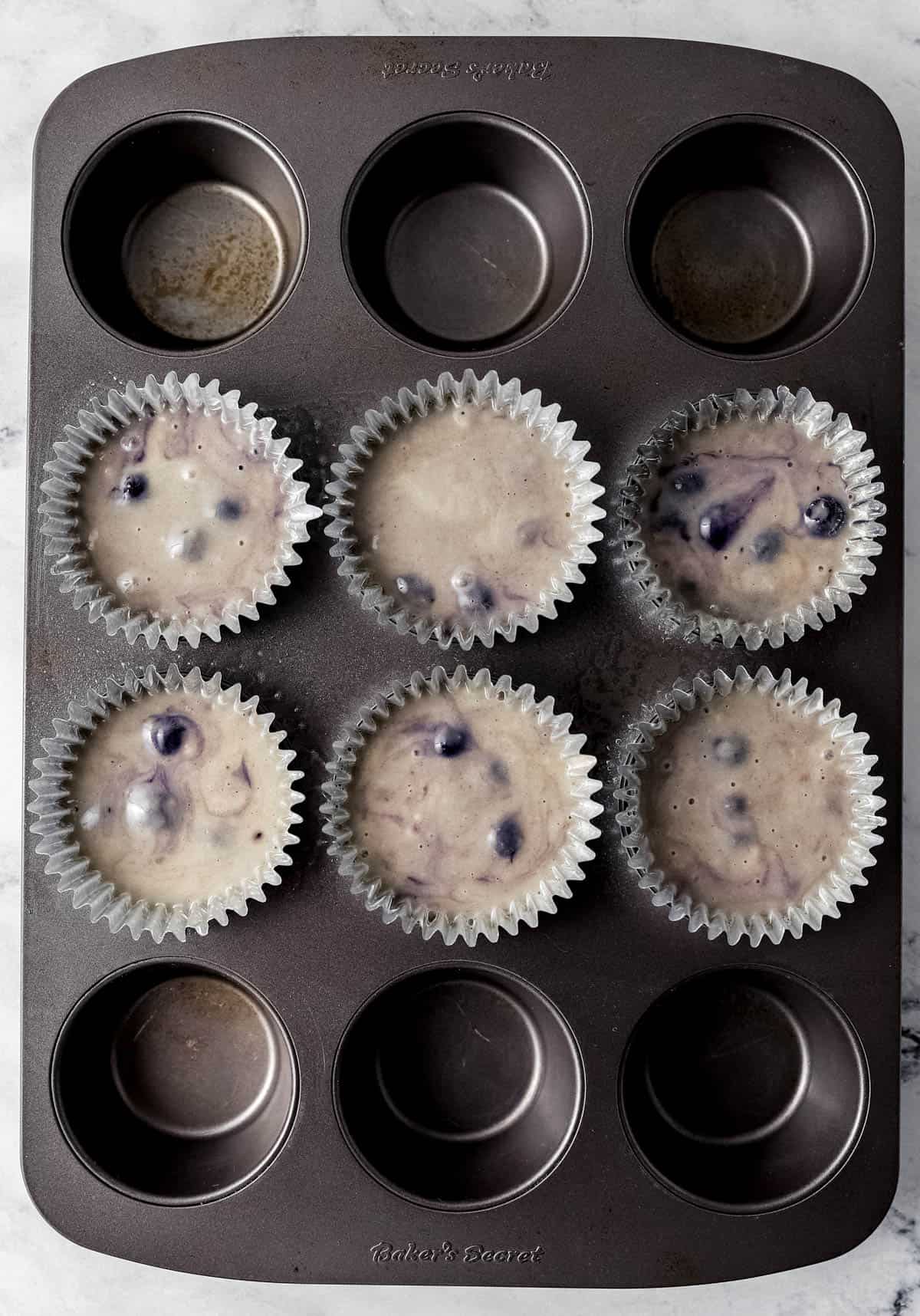 Muffin batter added to baking cups in muffin pan before baking.