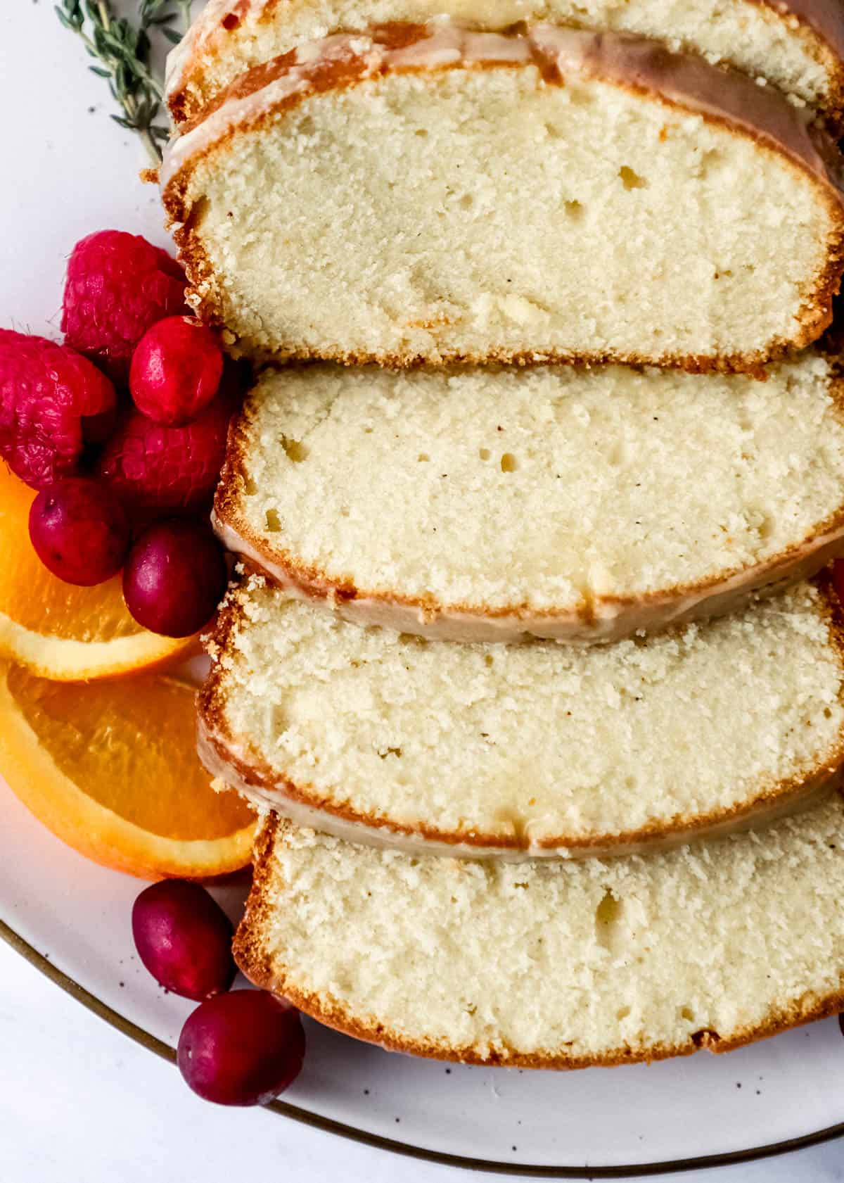 Slices of cake on white platter with fruits on it as well. 