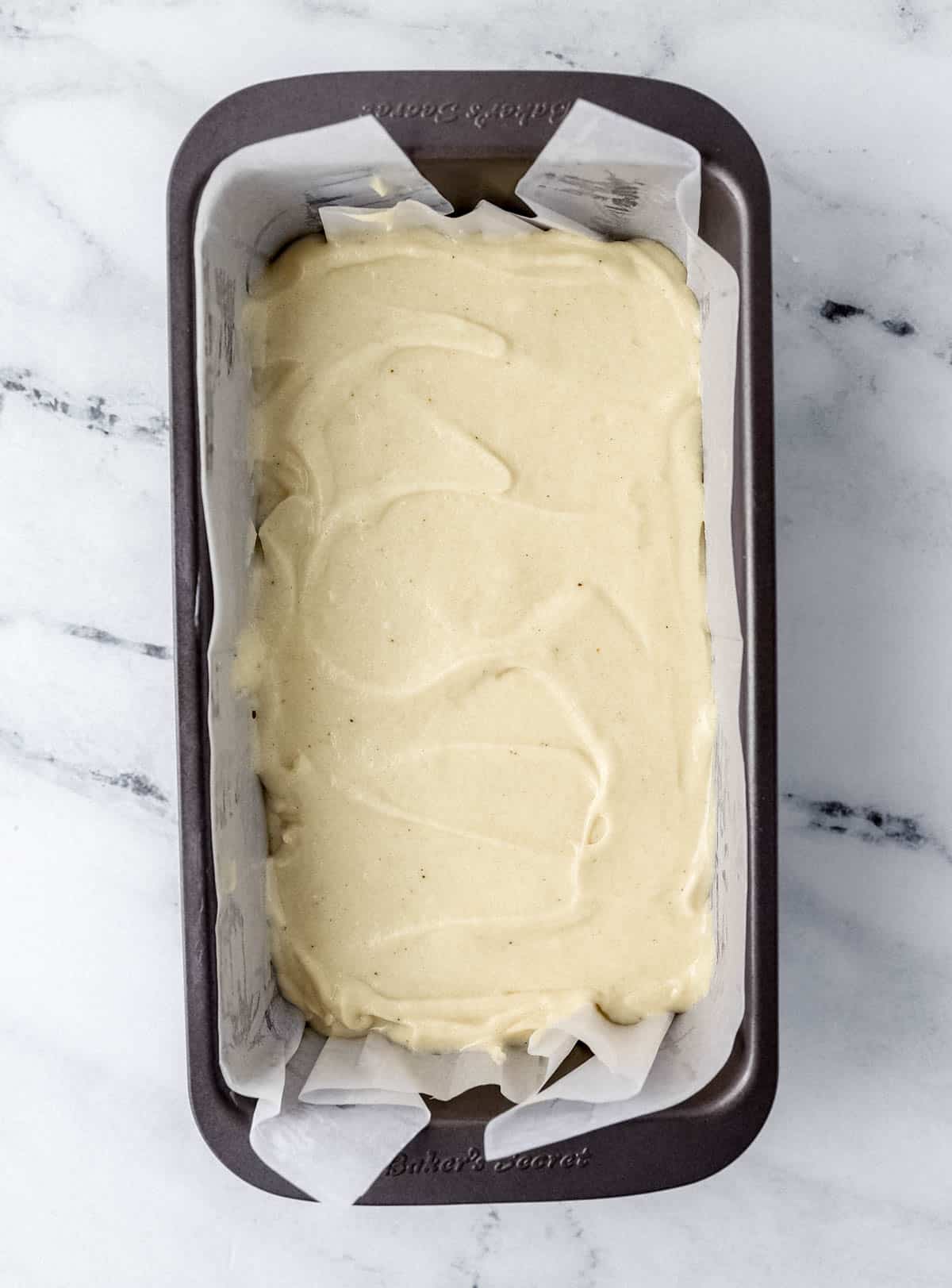 Cake mixture added to parchment lined loaf pan. 