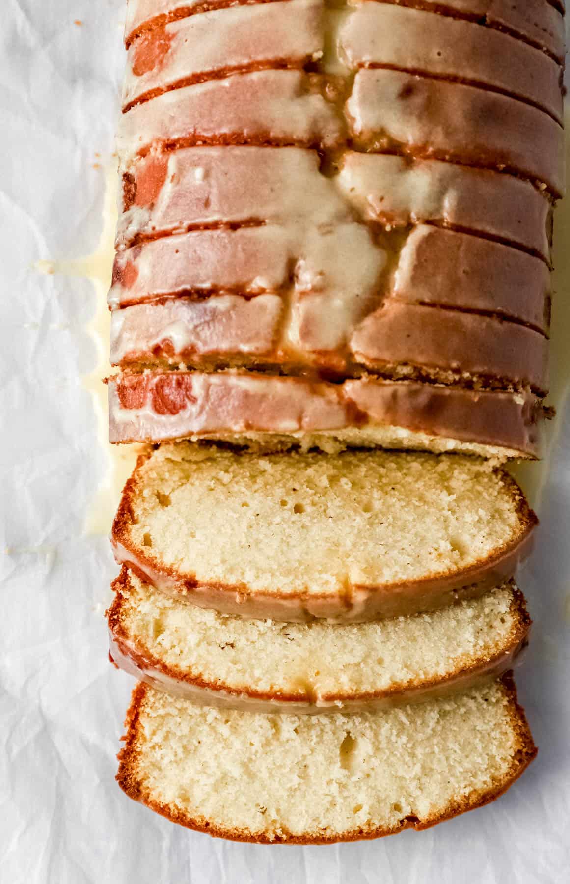 Baked cake topped with glazed and sliced on parchment paper. 