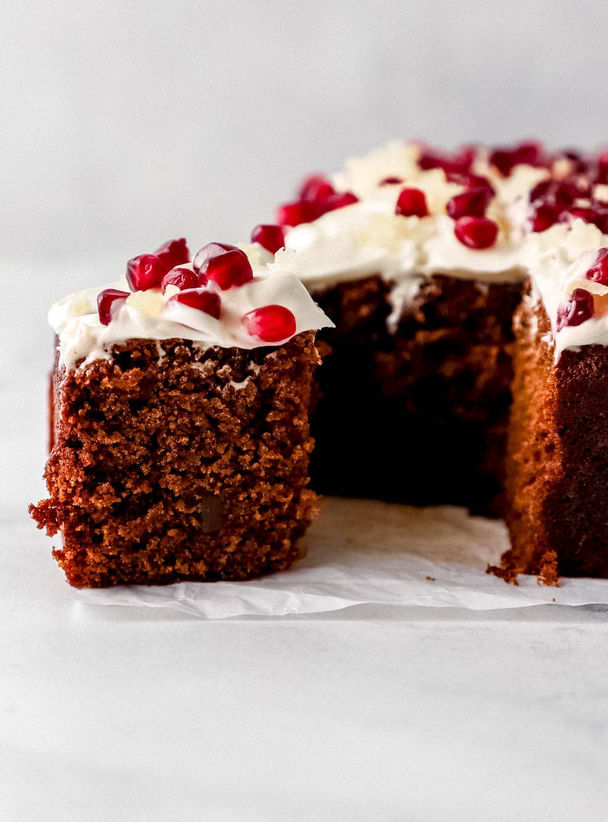 Close up side view of slice of gingerbread cake with the rest of the cake on parchment paper.