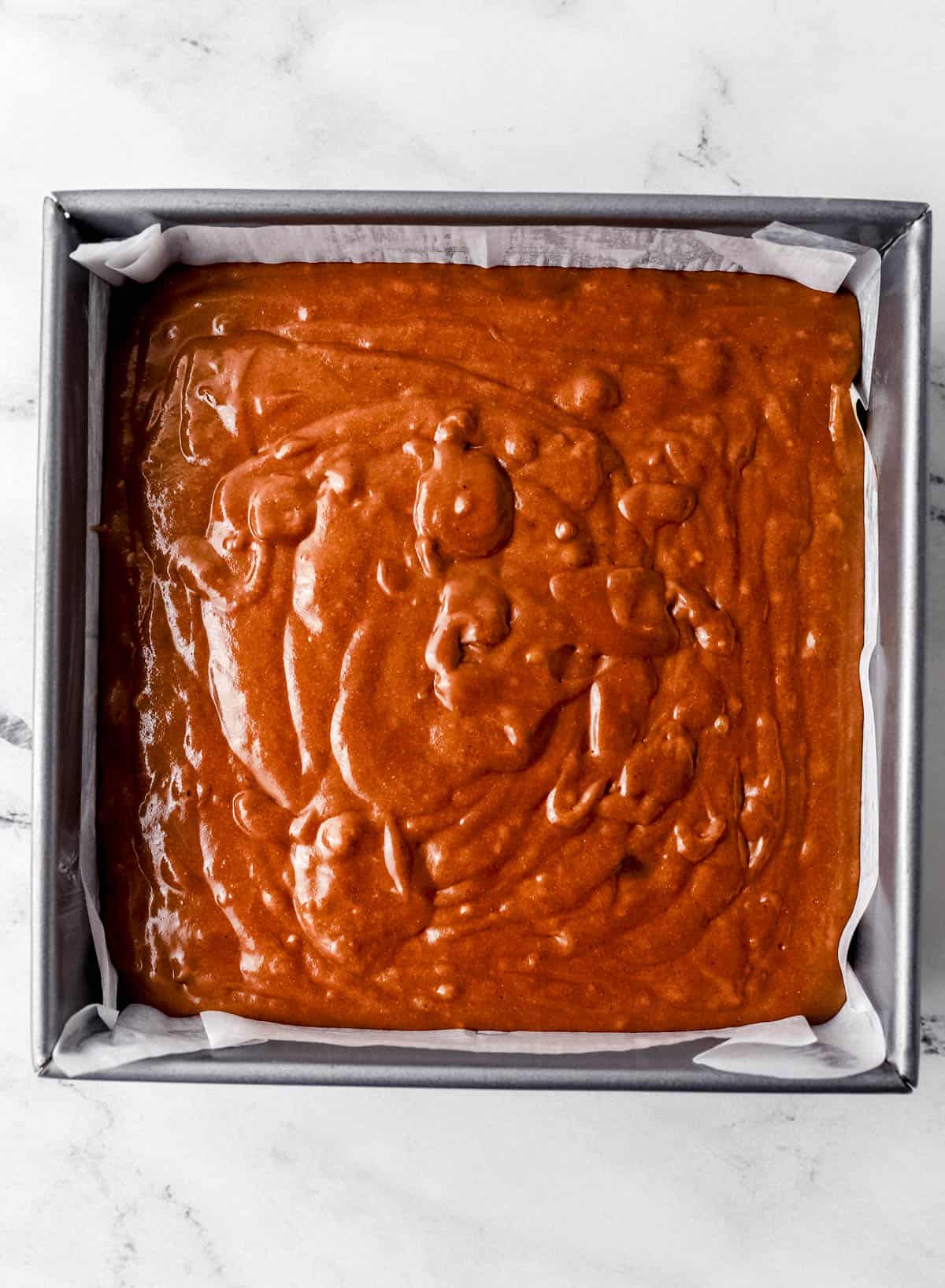 Gingerbread cake mixture added to parchment lined baking dish.