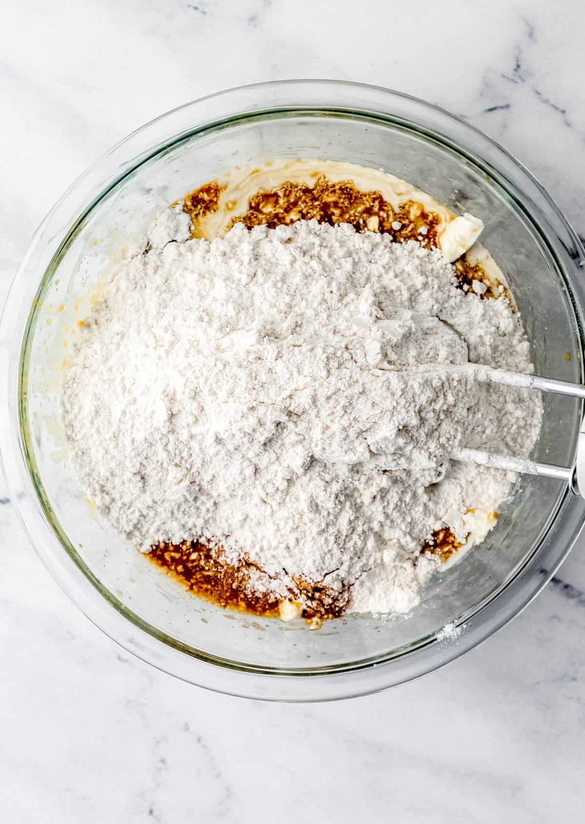 Flour mixture added to the other muffin ingredients in a large glass mixing bowl with hand mixer. 