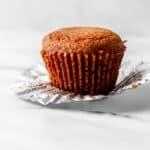 Close up side view of single muffin on top of muffin liner.