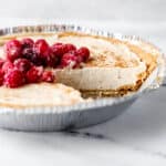 Close up side view of cheesecake with a slice cut out of it.