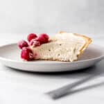 Close up side view of slice of cheesecake on small white plate.