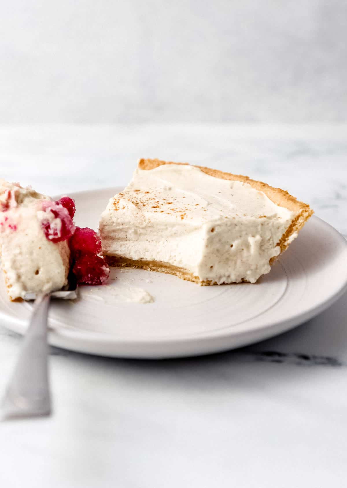 Slice of cheesecake on a white plat with a fork in it. 