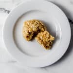 Overhead view of cookie on white plate cut in half.
