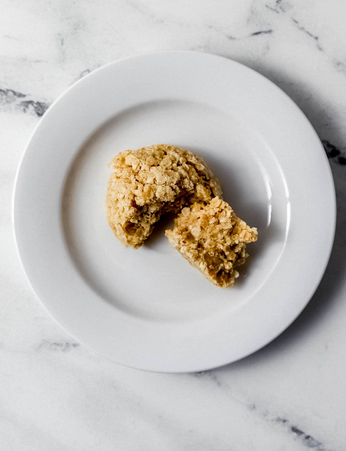 Overhead view of single cookie on small white plate cut in half. 