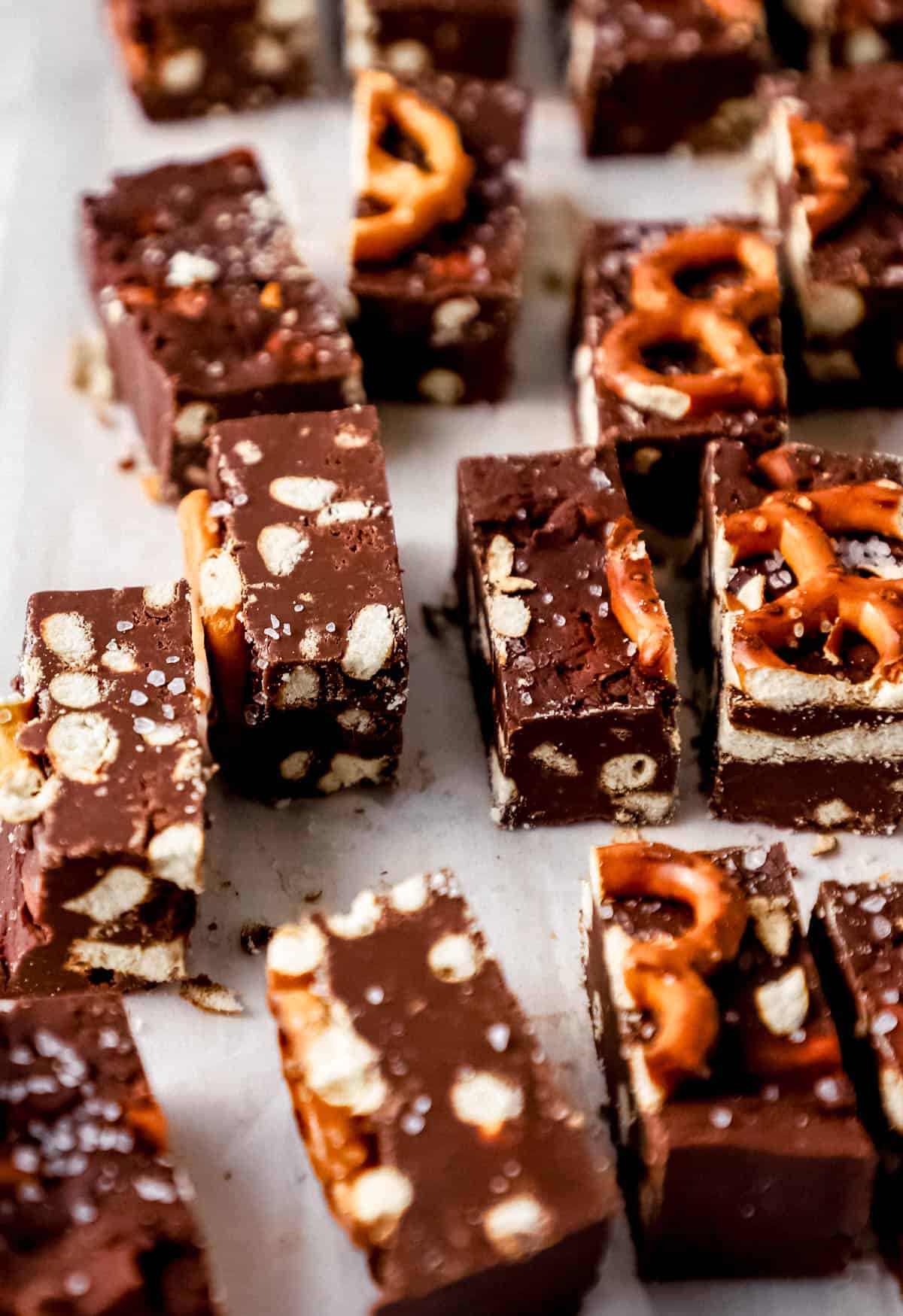 Close up side view of finished fudge cut into small squares on parchment paper. 