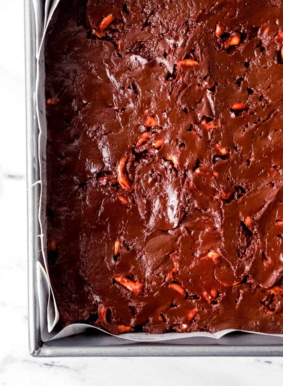 Chocolate mixture with pretzels added in parchment lined baking pan. 