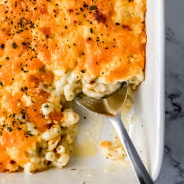 Overhead view of baked mac and cheese in baking dish with serving spoon in it.