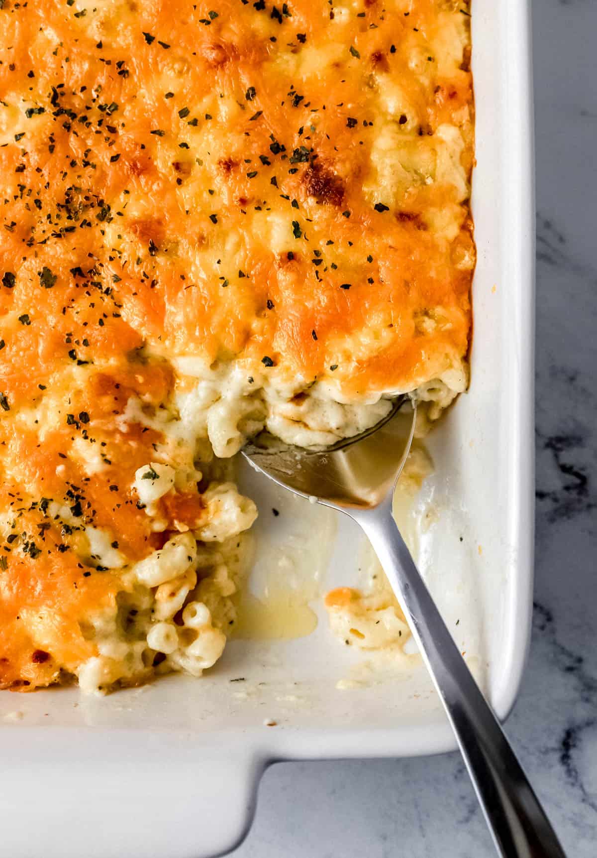 Baked mac and cheese in baking dish with serving spoon. 