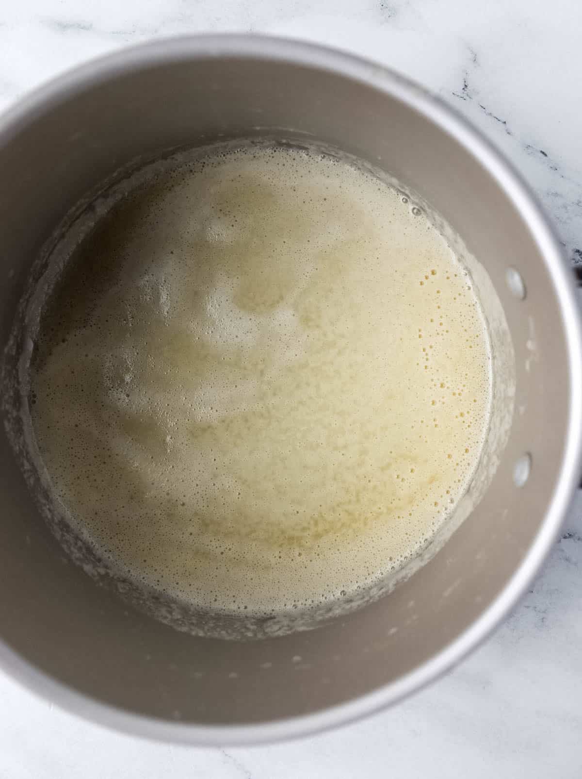 Melted butter in large stockpot on marble surface. 