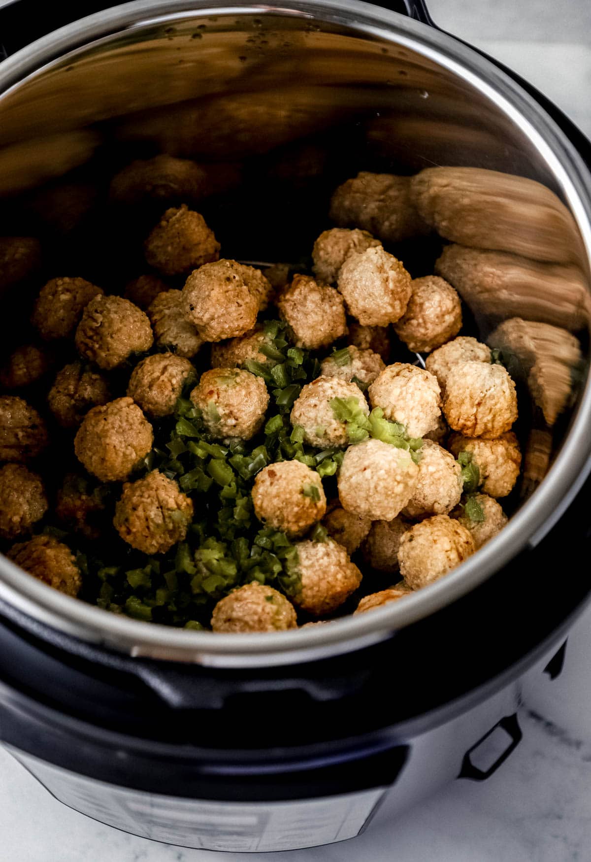 Close up view of cooked meatballs and jalapenos in instant pot pressure cooker. 