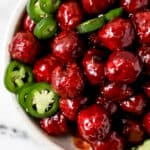 Close up view of meatballs in white bowl on marble surface.
