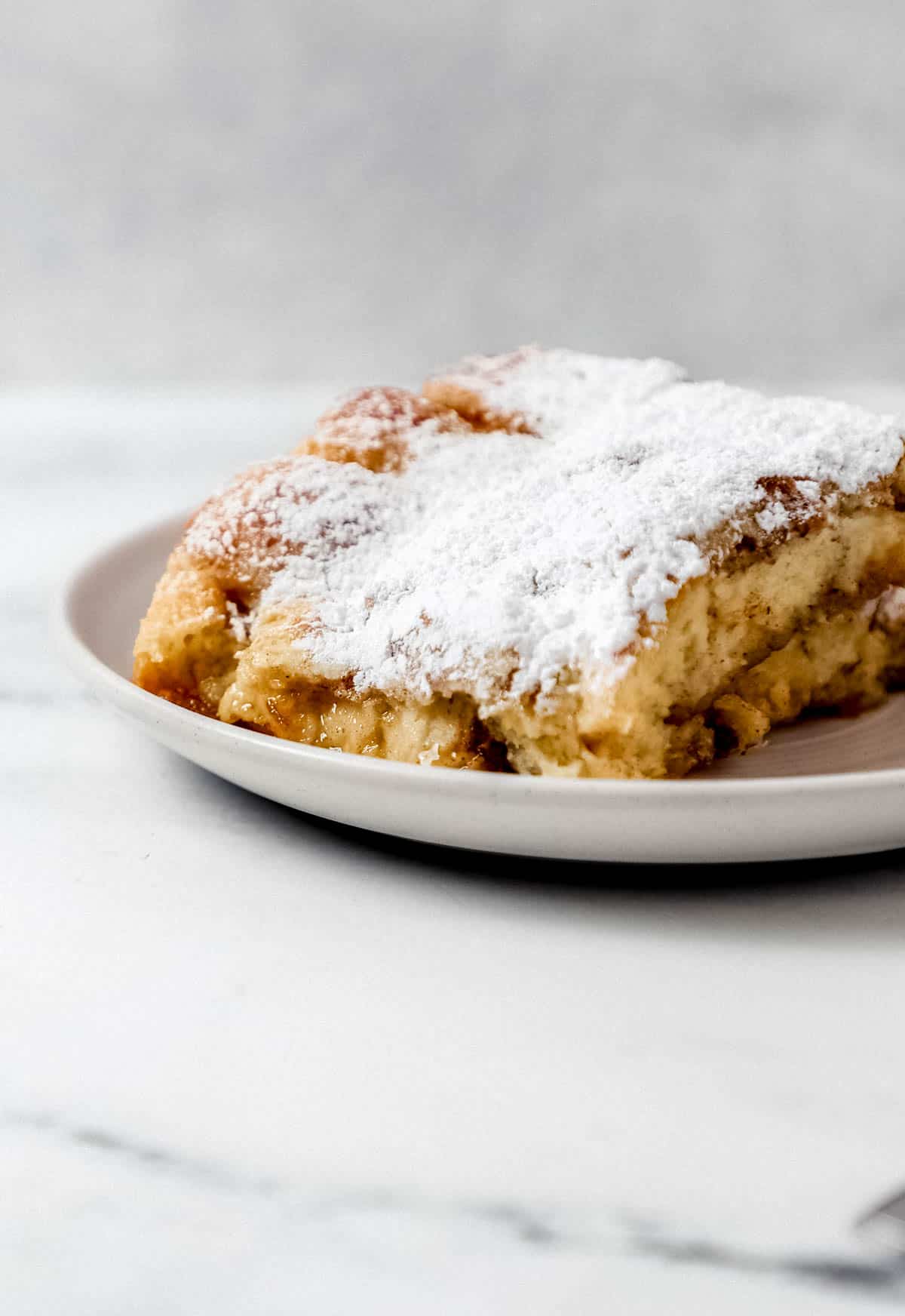 Close up side view of pieces of french toast on plate on marble surface. 