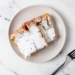 Overhead view of two pieces of french toast on white plate beside a fork.