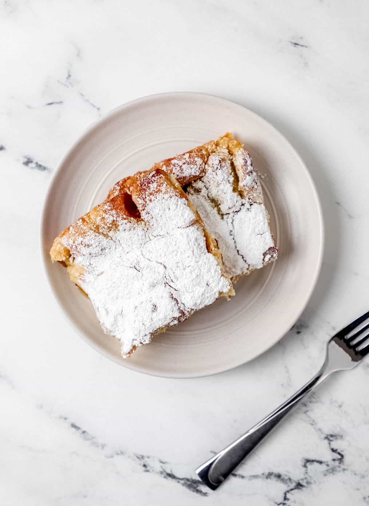 Overhead view of two pieces of baked french toast on plate beside a fork. 