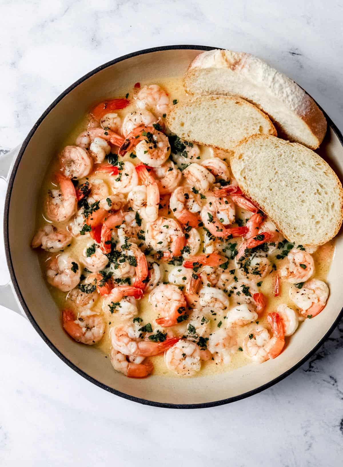 Overhead view of finished garlic butter shrimp in pan with pieces of bread in it. 