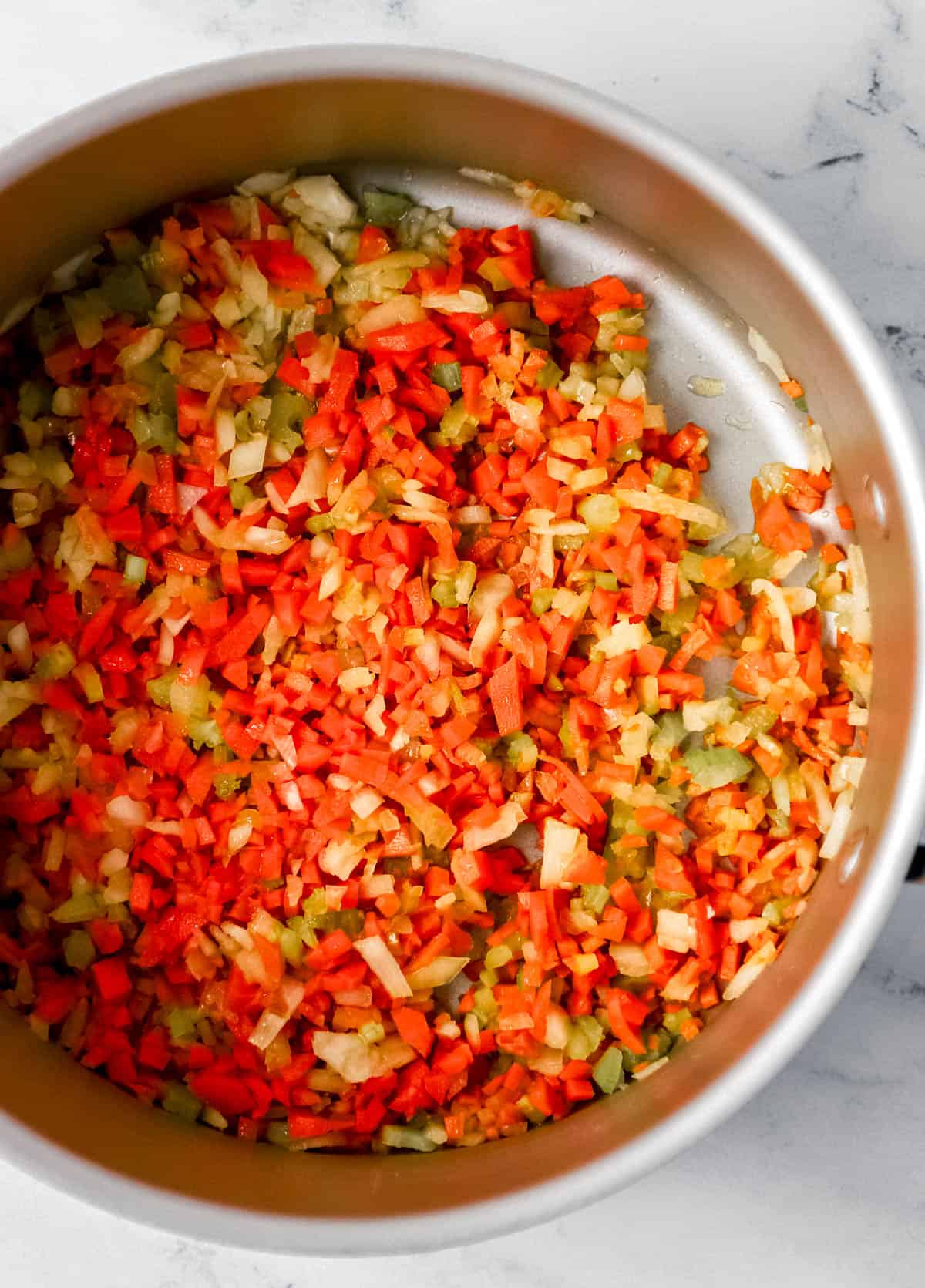 Overhead view of diced celery, carrots, and onion in large pot. 