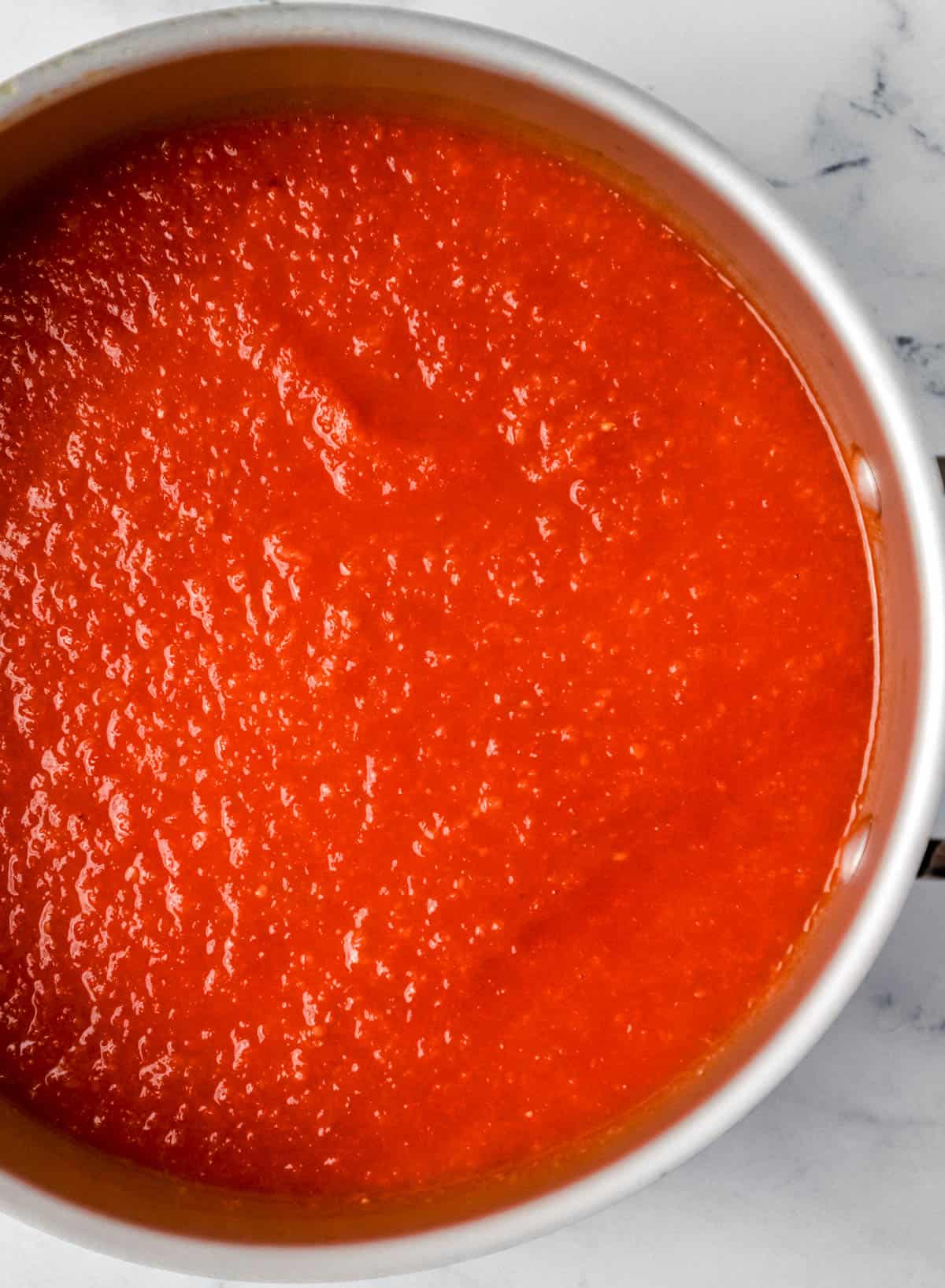 Overhead view of pureed tomatoes and vegetables in large pot. 