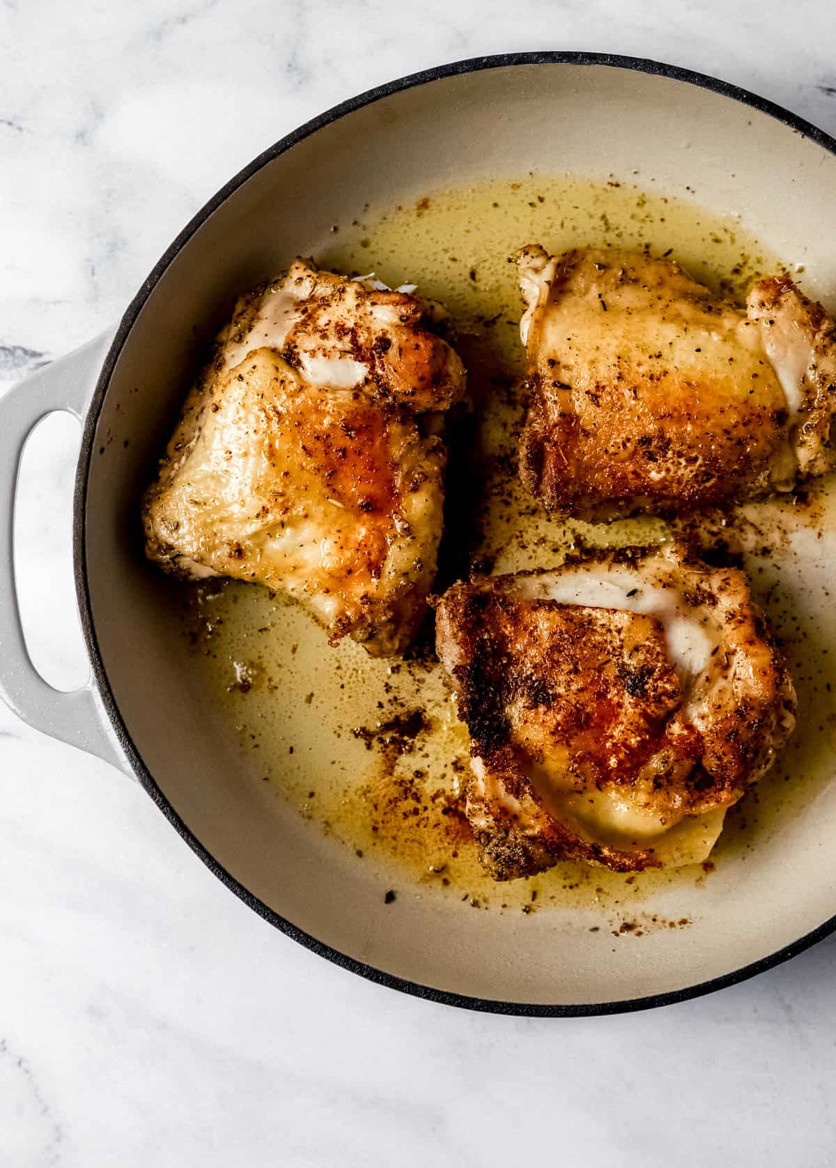 Seared chicken thighs in braiser pan with olive oil. 