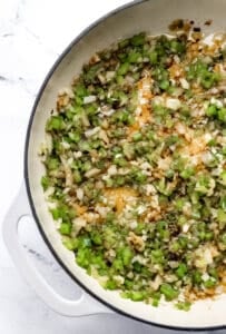 Overhead view of pepper and onion cooking in braiser.
