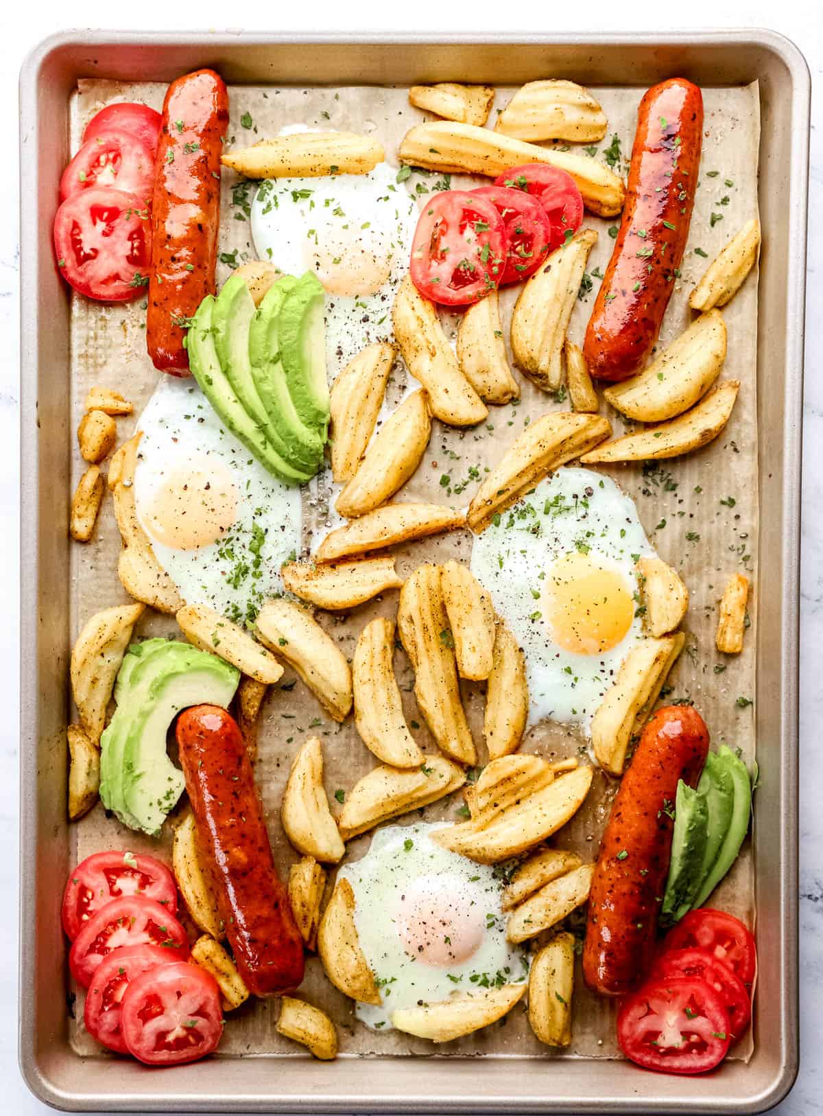 Overhead view of finished sheet pan breakfast on parchment lined baking sheet. 