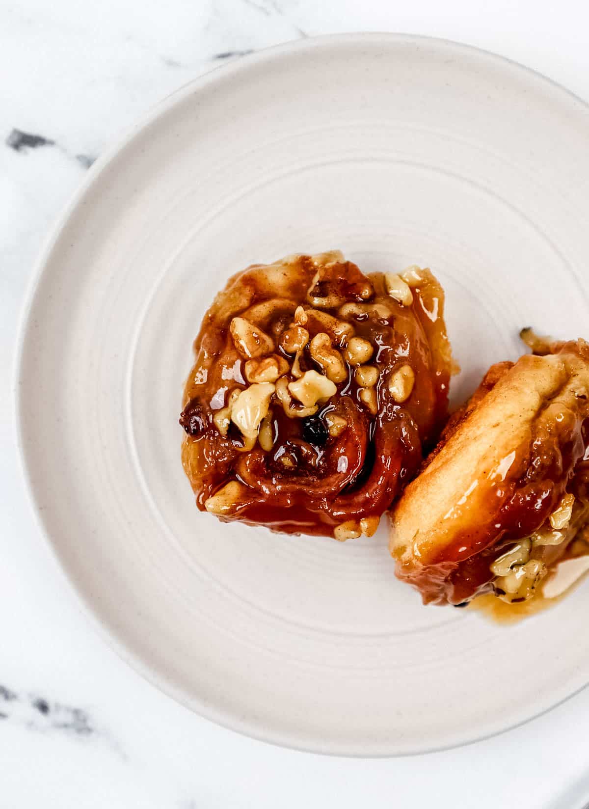 Overhead view of two finished sticky buns on a plate. 