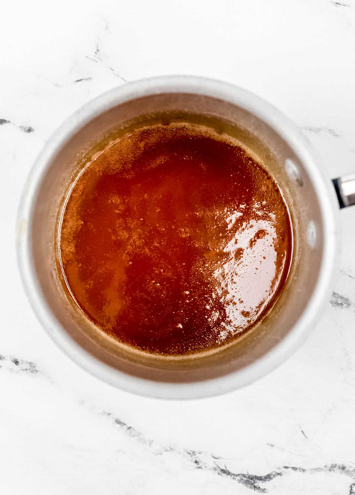 Sticky mixture in small saucepan on marble surface. 