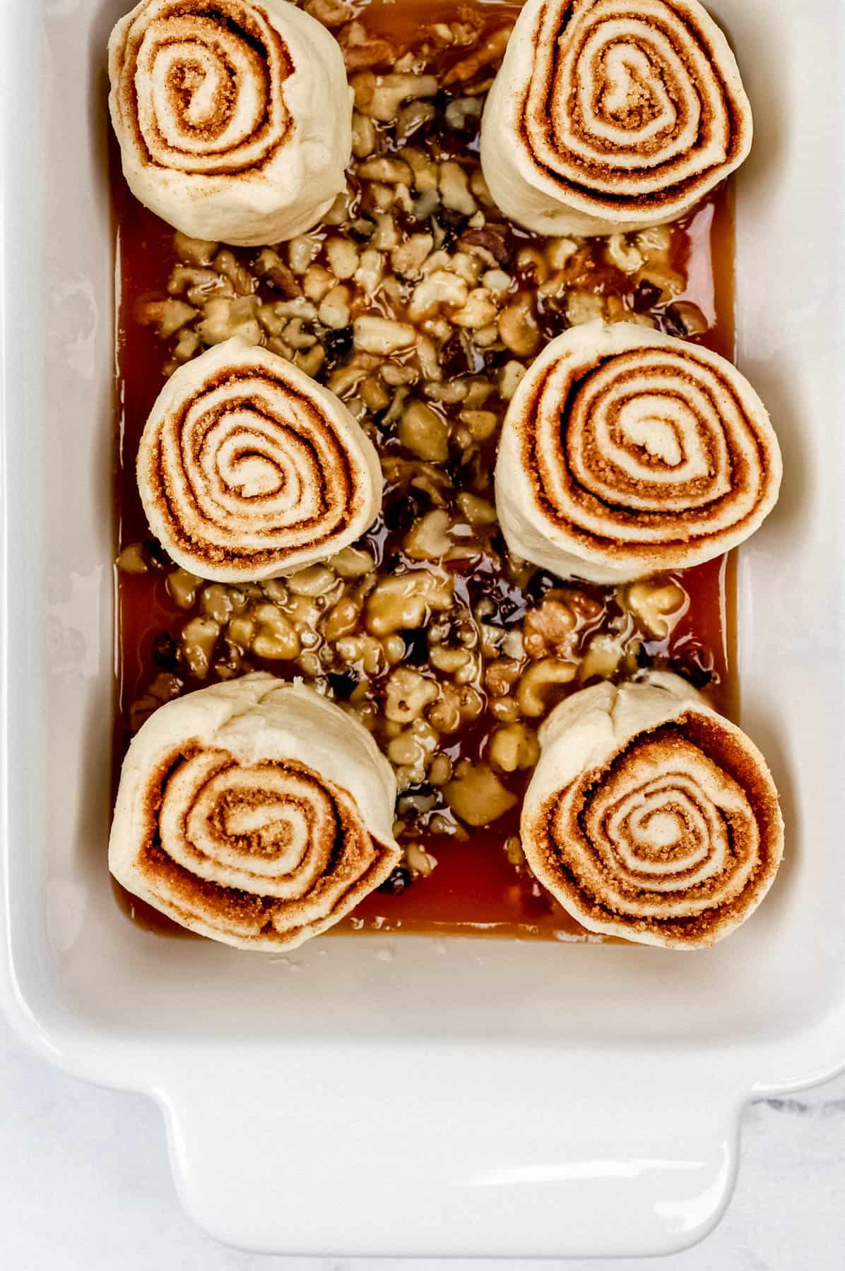 Rolls added to prepared baking dish on top of walnut mixture. 