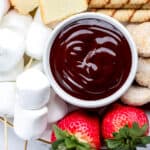 Close up of chocolate fondue in white bowl on dessert board.